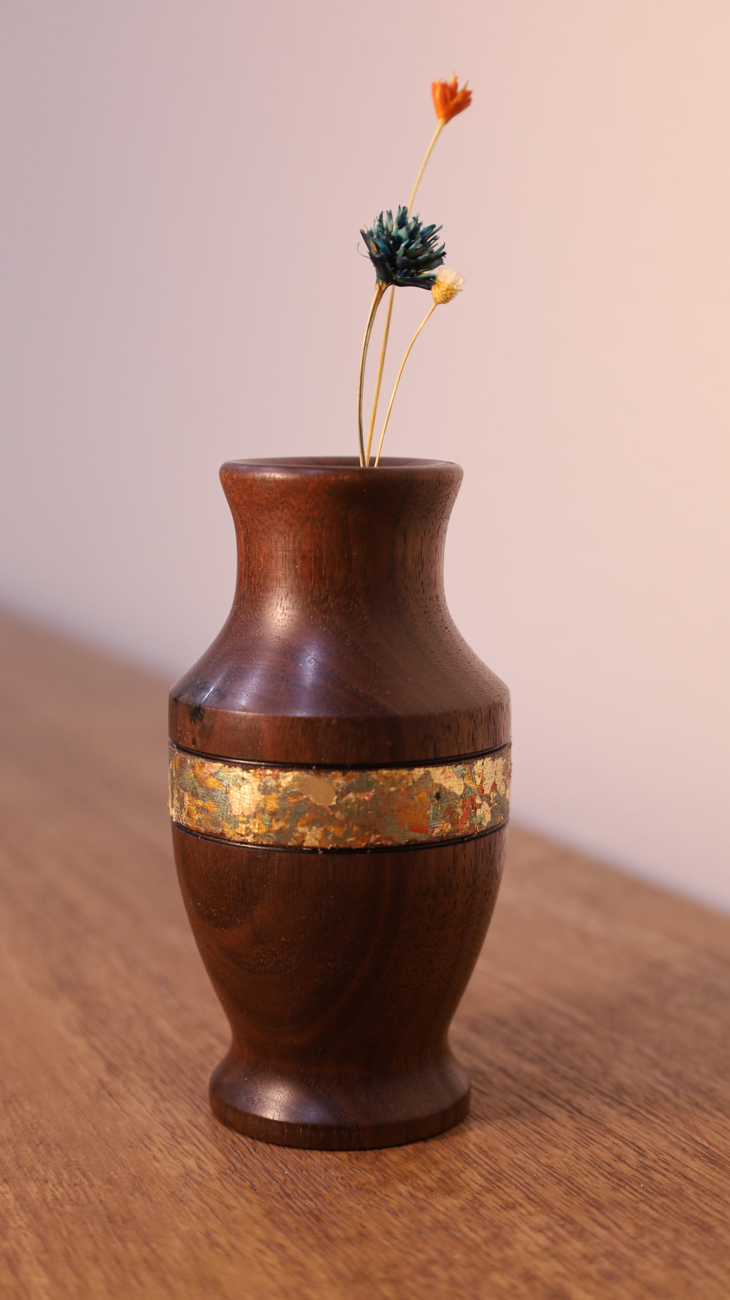 Wooden vase with gold band on a wooden surface