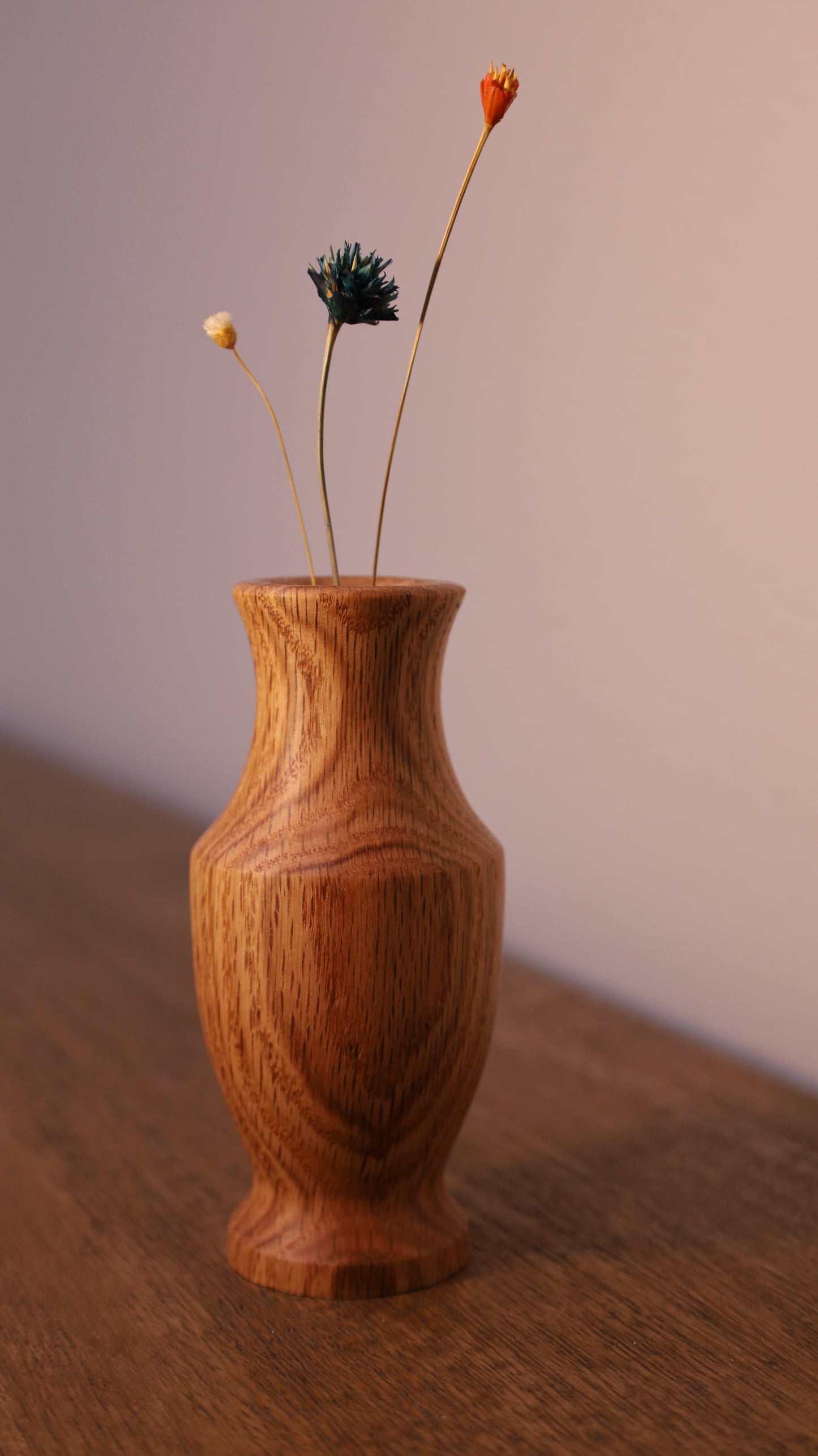 Wooden vase with a dried flower arrangement on a wooden surface