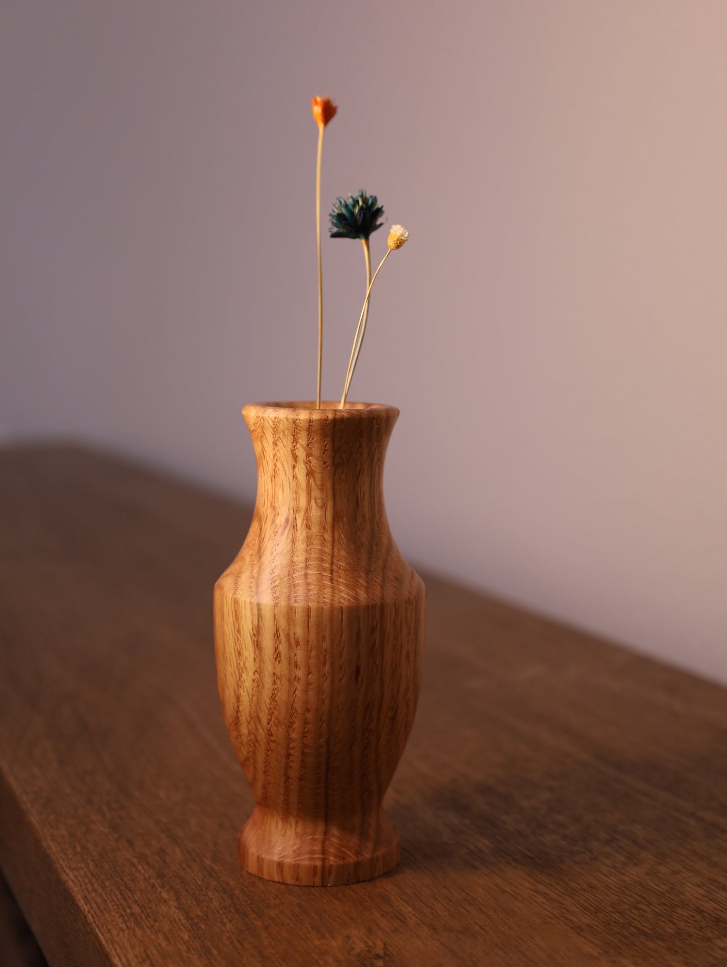 Wooden vase with dried flowers on a wooden surface