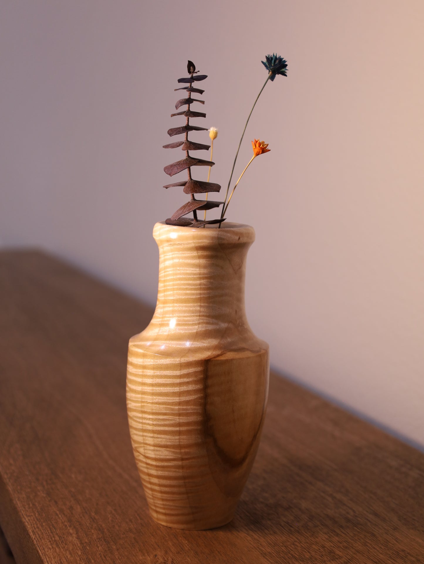 Wooden vase with a small plant on a wooden surface