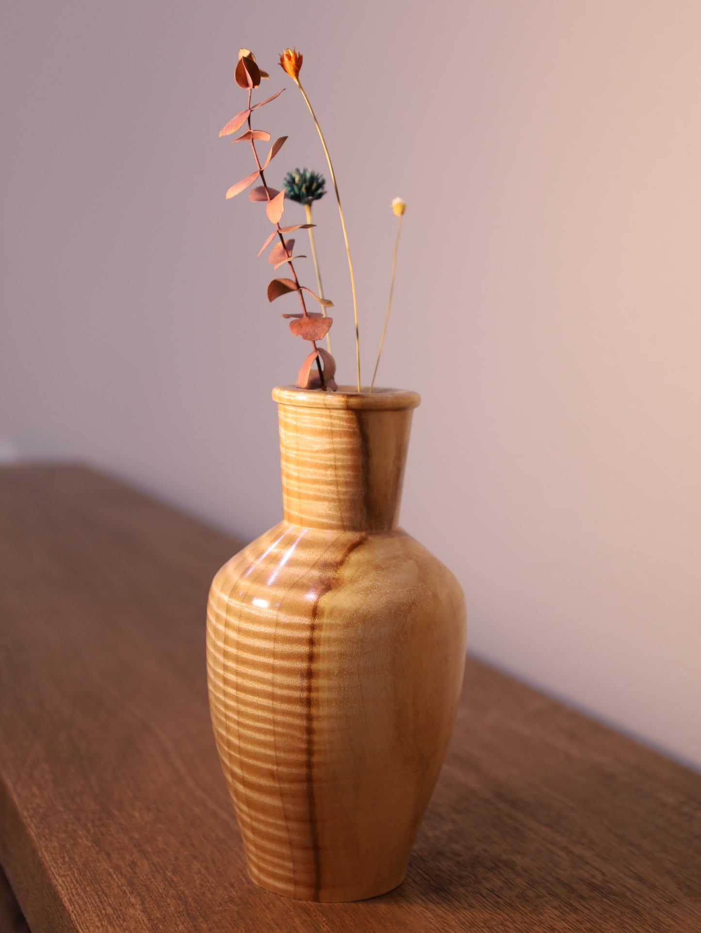 Wooden vase with a plant on a wooden surface