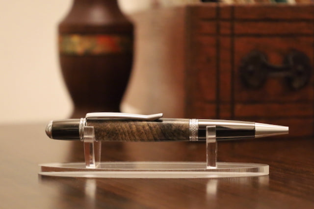 custom Pen on a clear stand with a wooden and metal design, placed on a wooden surface.