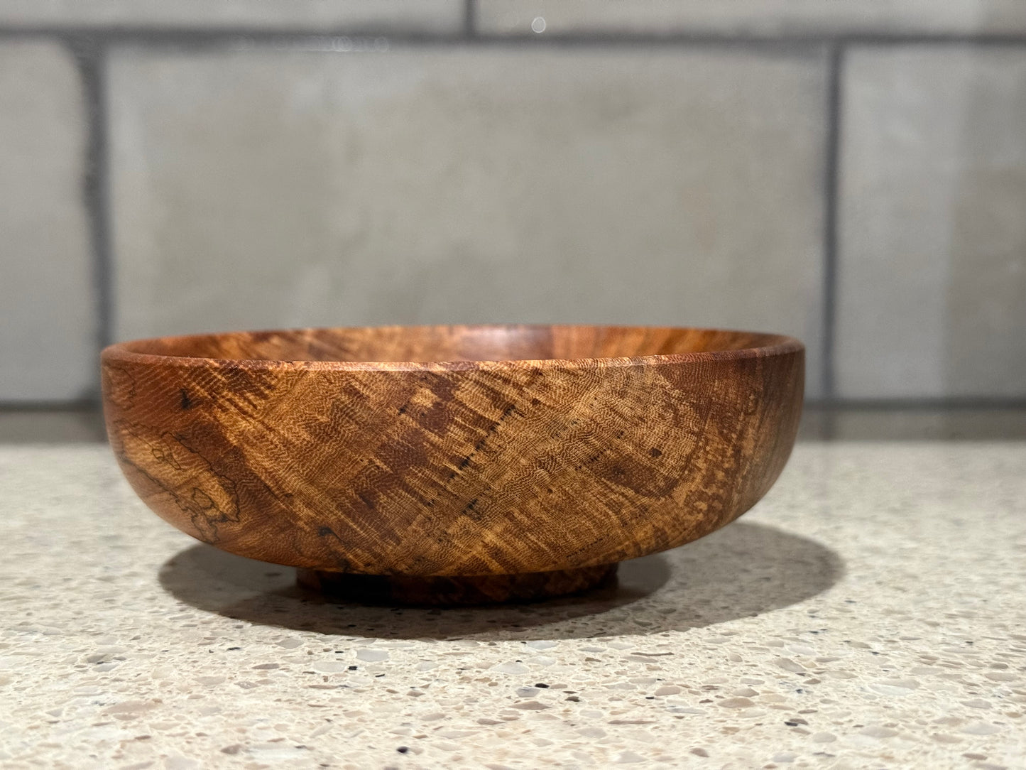 Wooden bowl on a kitchen counter with a tiled wall background