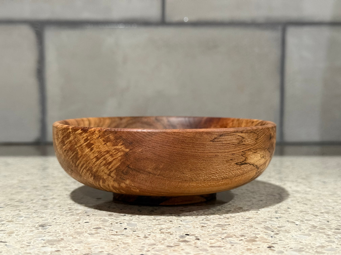 Wooden bowl on a kitchen counter with a tiled wall background