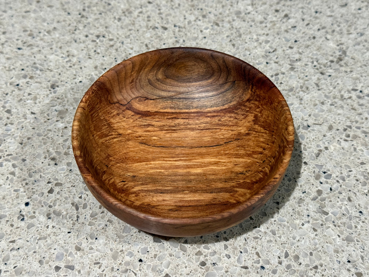 Wooden bowl on a kitchen counter with a tiled wall background