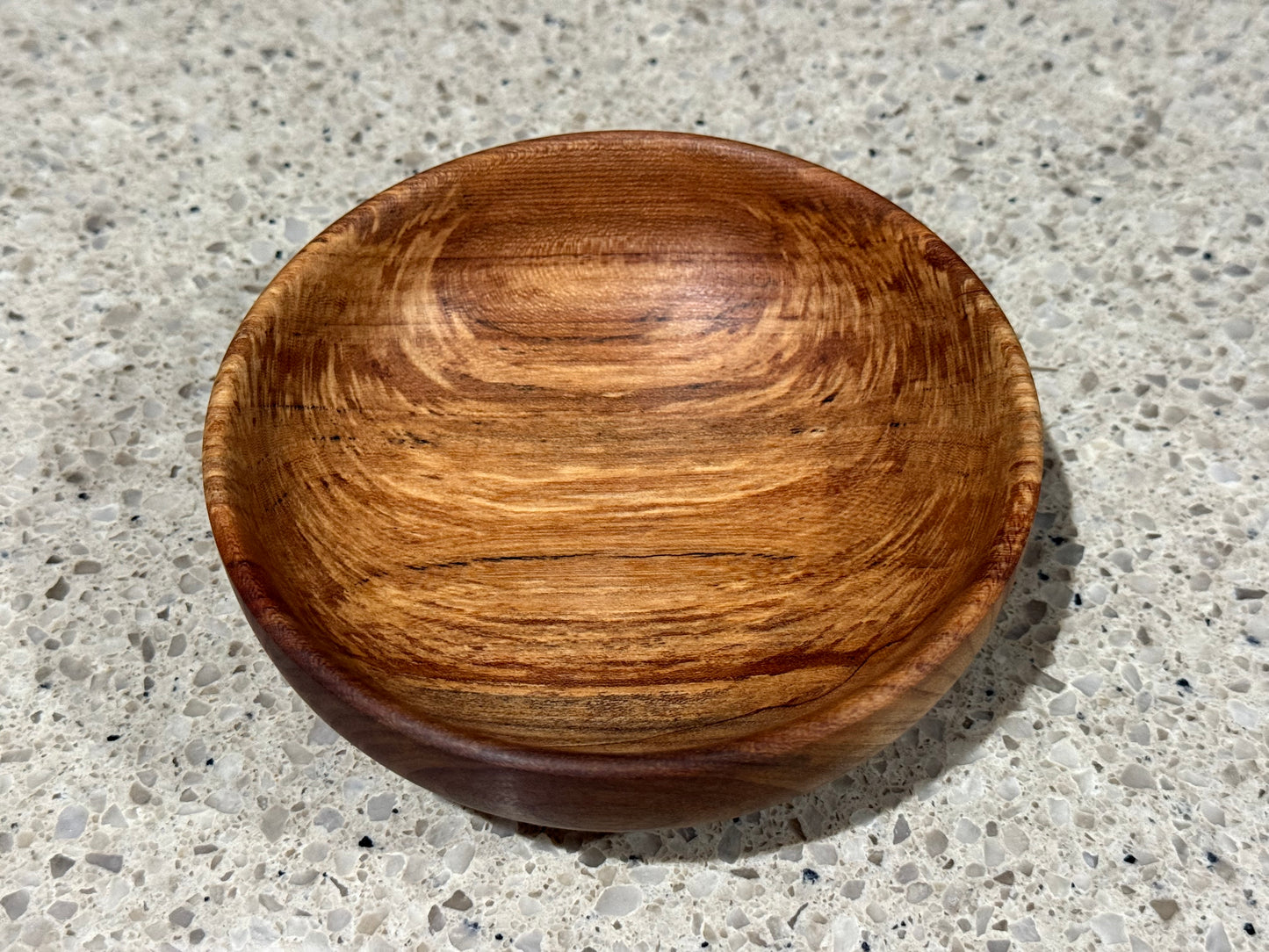 Wooden bowl on a kitchen counter with a tiled wall background