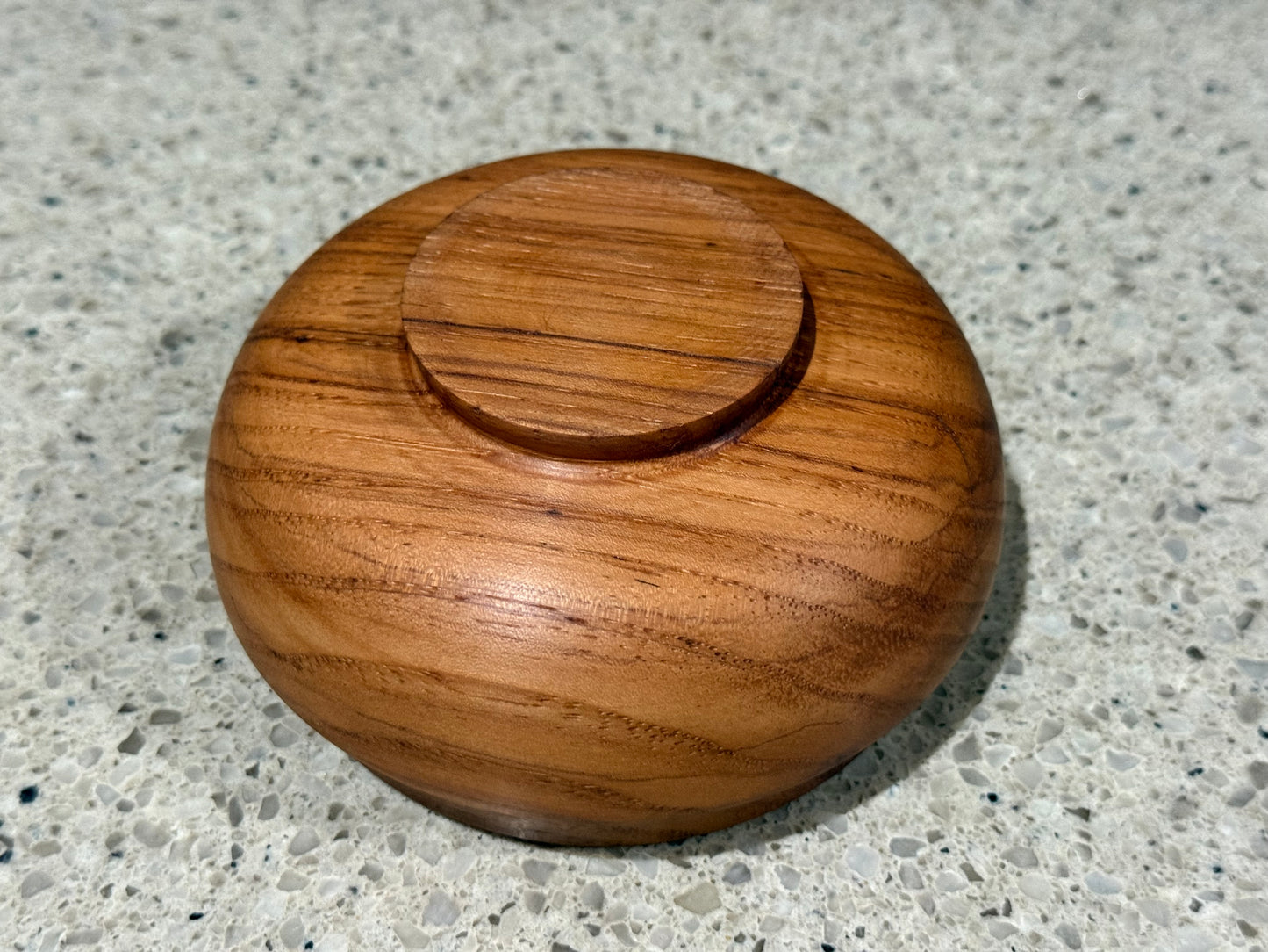 Wooden container lid on a speckled gray surface