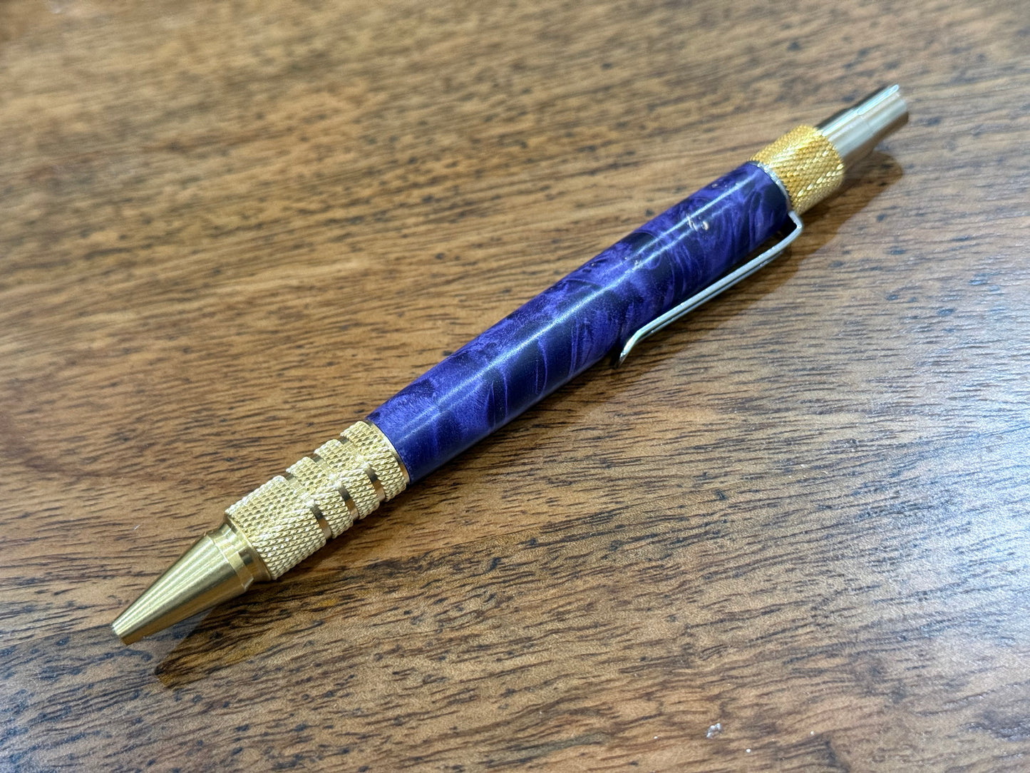 Pen with purple and gold design on a wooden surface