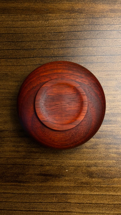 A decorative African lidded ring bowl made of African Padouk wood with a lid made of African Teak, placed on a wooden surface.