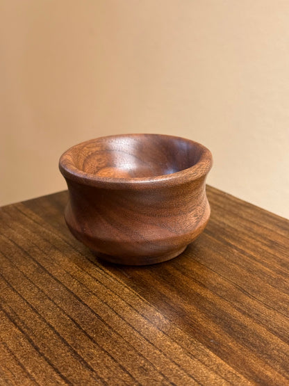 A small walnut ring bowl placed on a wooden surface.