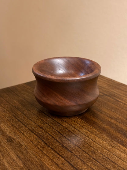 A small walnut ring bowl placed on a wooden surface.
