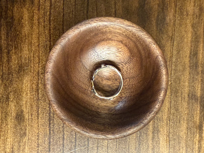 A small walnut ring bowl placed on a wooden surface.