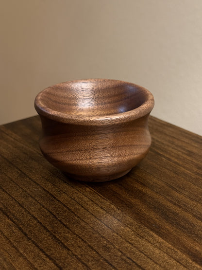 A small walnut ring bowl placed on a wooden surface.