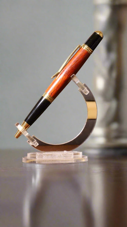 Luxury pen with wooden and gold accents on a stand against a gray background