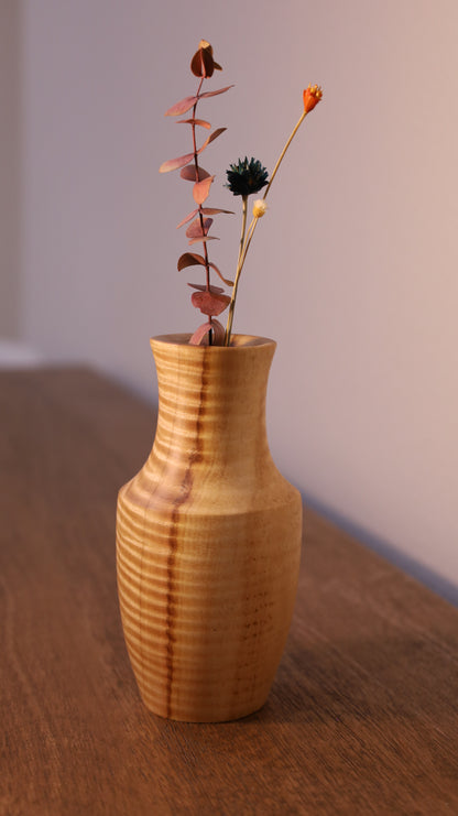 Wooden vase with a branch of dried leaves on a wooden surface