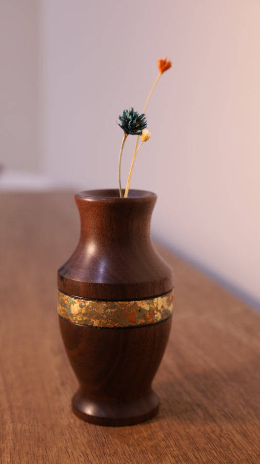 Wooden vase with gold band on a wooden surface