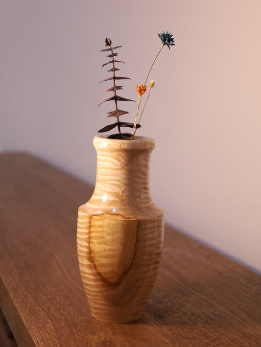 Wooden vase with a plant on a wooden surface