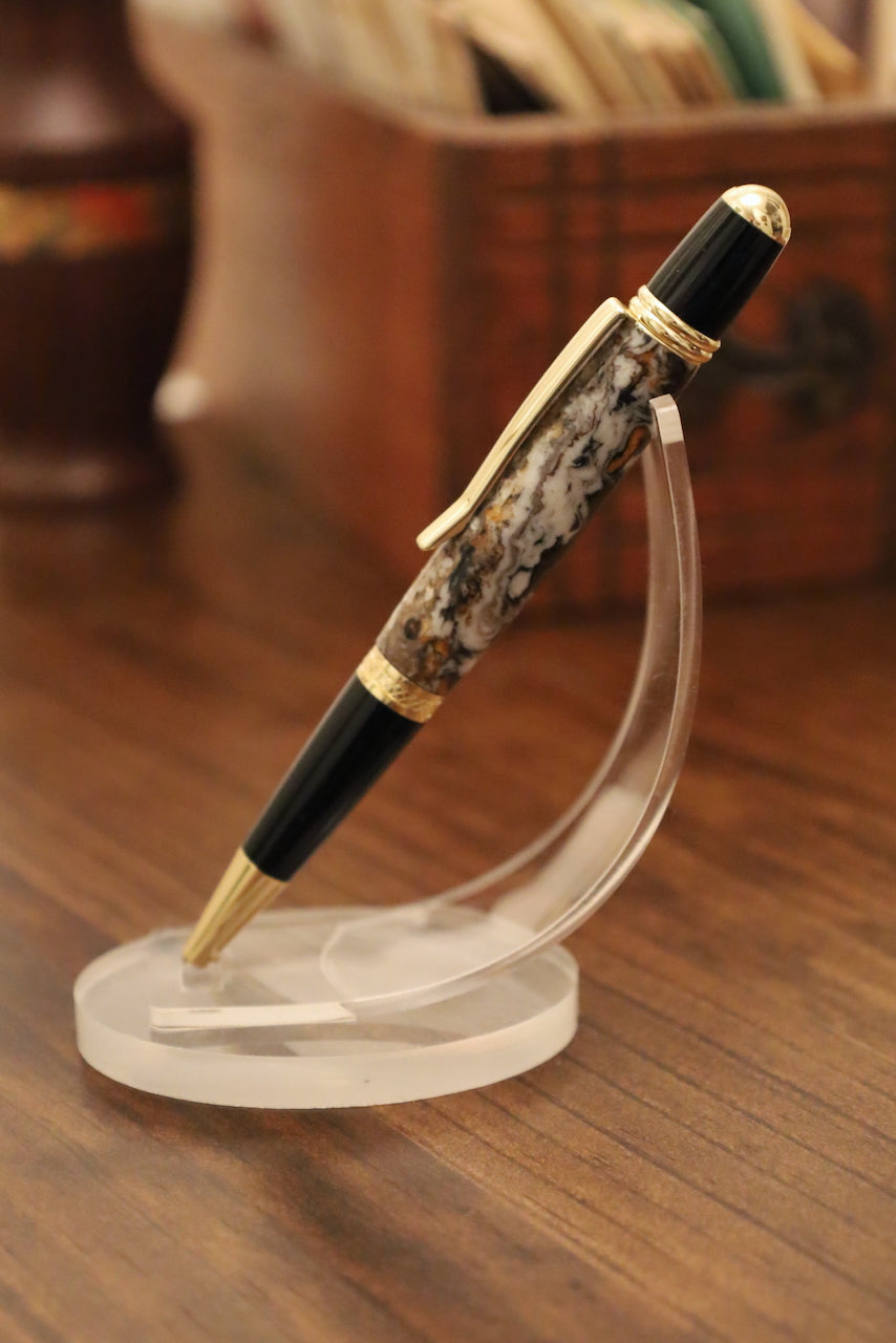 Luxury pen with decorative cap on a clear stand against a blurred background
