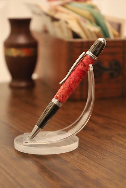 custom Pen with red barrel and silver accents on a clear stand on a wooden surface.