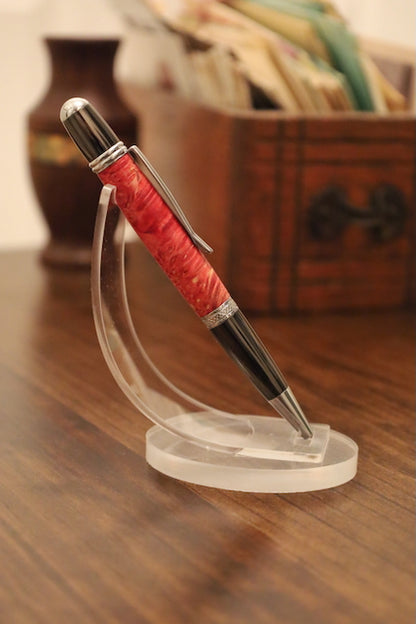 custom Pen with red barrel and silver accents on a clear stand on a wooden surface.