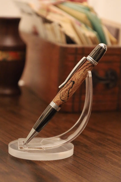 custom Pen with wooden grip on a clear stand on a wooden surface