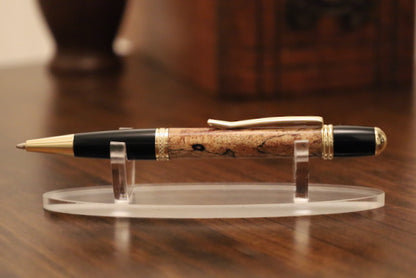 custom  wooden Pen with black and gold accents on a clear stand against a blurred background