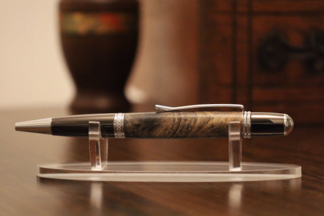 custom Pen on a clear stand with a wooden and metal design, placed on a wooden surface.