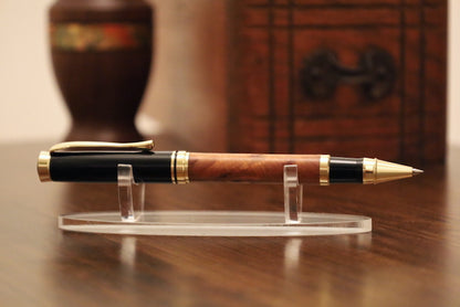Wooden pen with gold accents on a clear stand against a wooden background