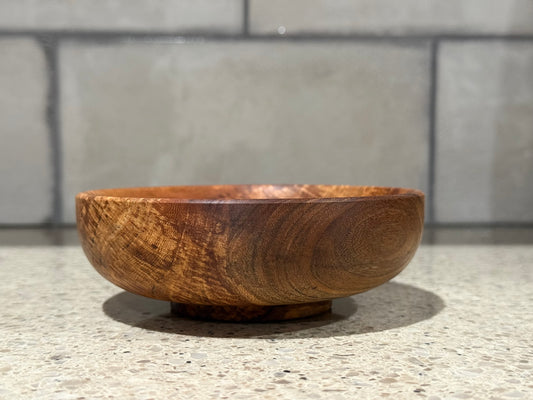 Wooden bowl on a kitchen counter with a tiled wall background