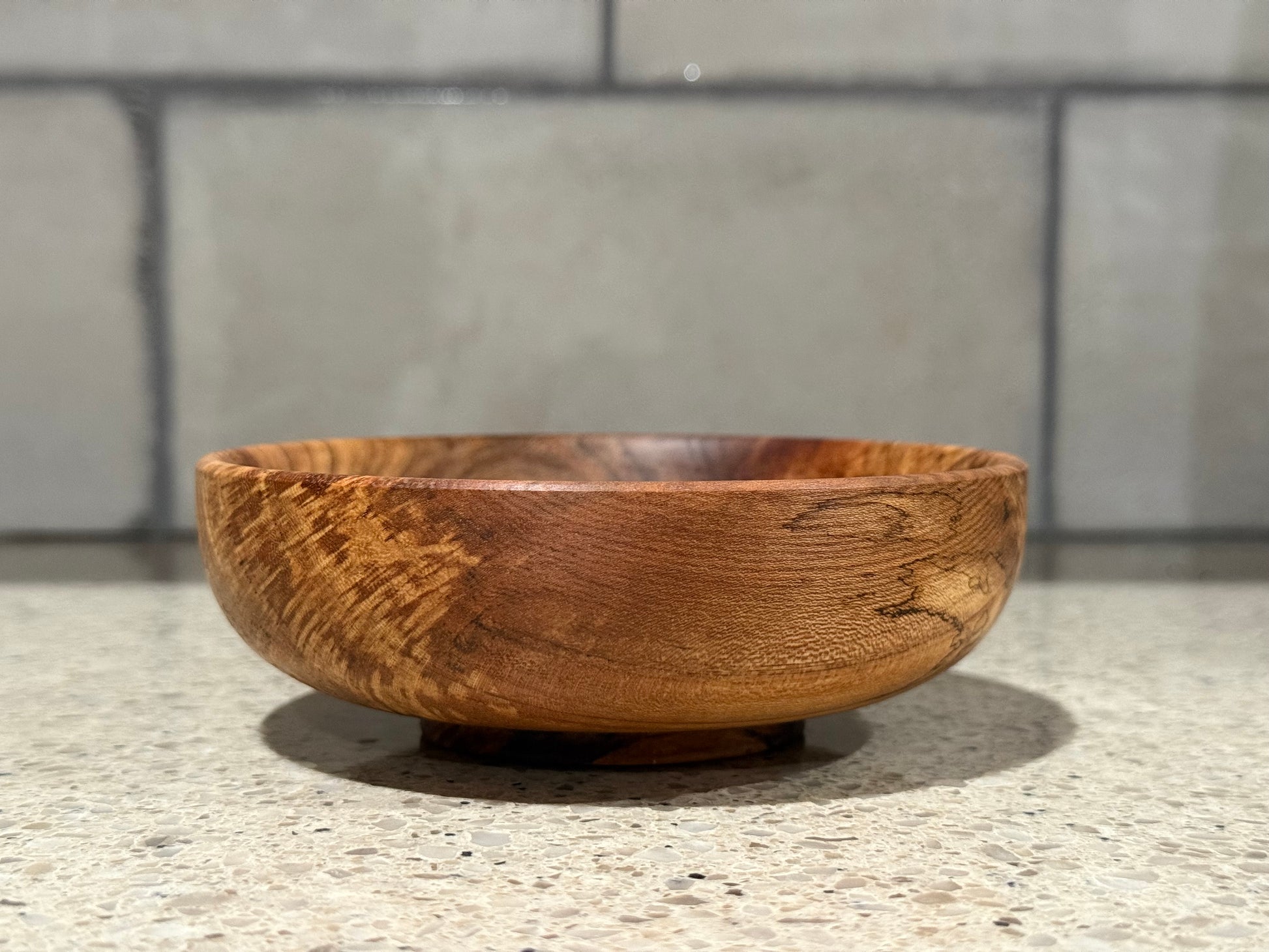 Wooden bowl on a kitchen counter with a tiled wall background