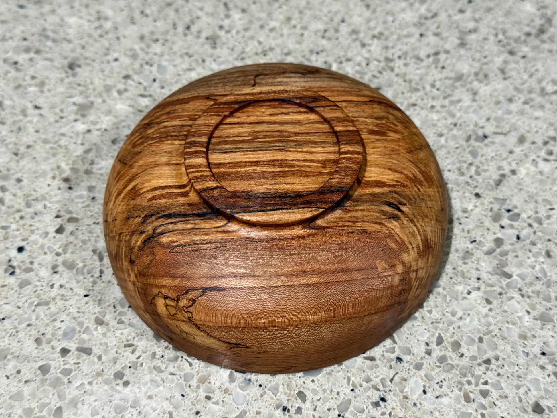 Wooden bowl on a kitchen counter with a tiled wall background