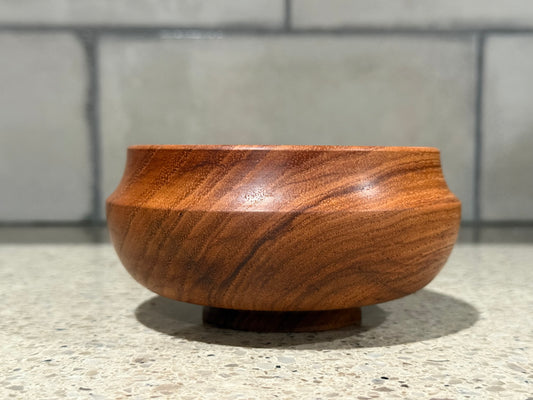 Wooden bowl on a concrete surface with a tiled wall background