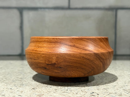 Wooden bowl on a concrete surface with a tiled wall background