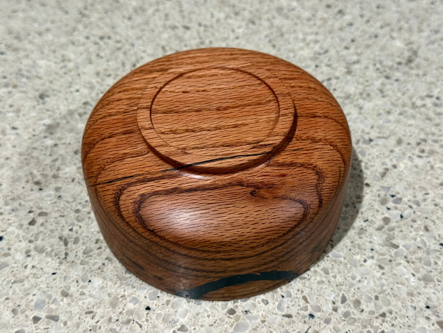 Wooden bowl with a black interior on a kitchen counter with a tiled wall background