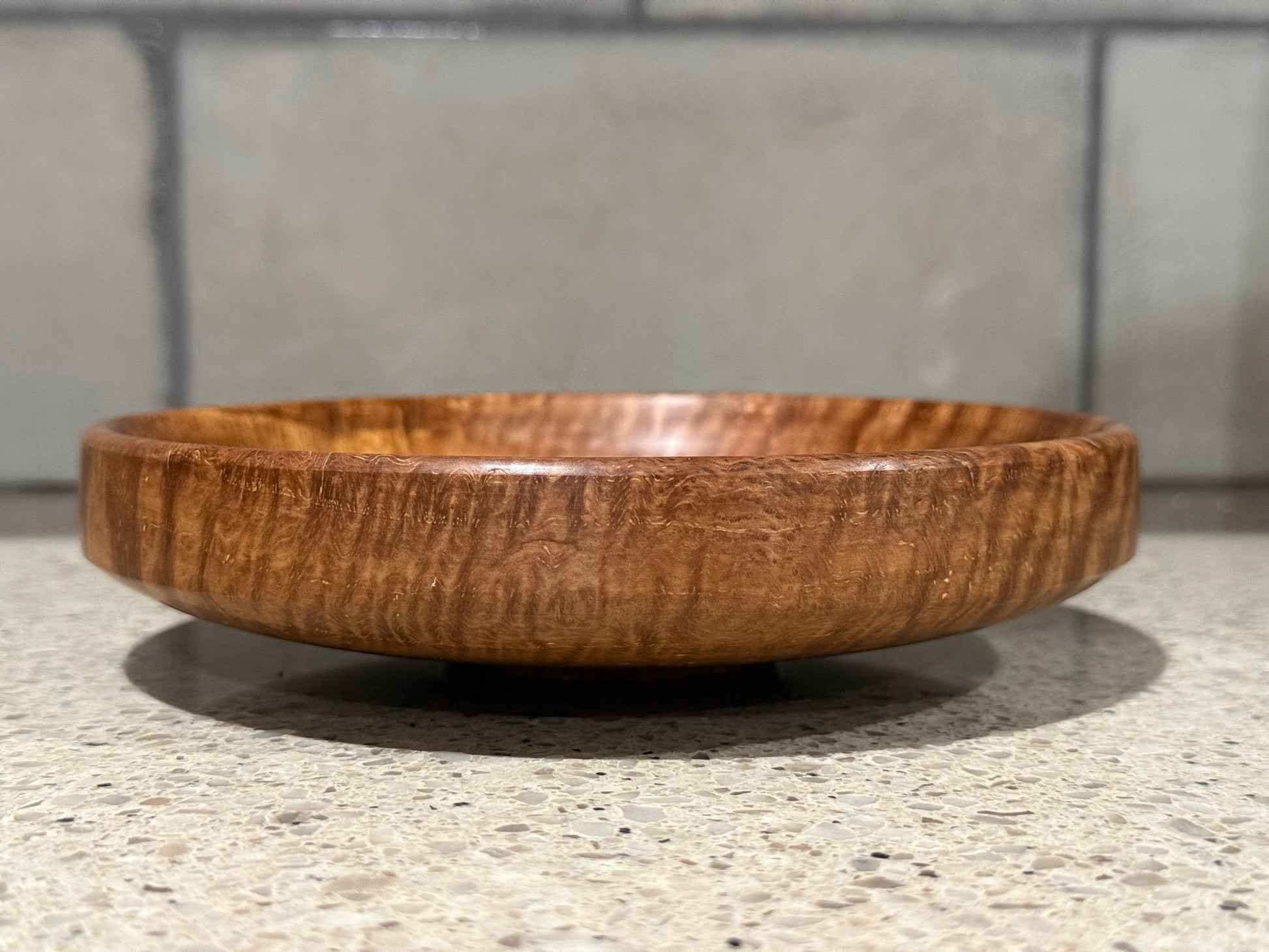Wooden bowl on a kitchen counter with a tiled wall background