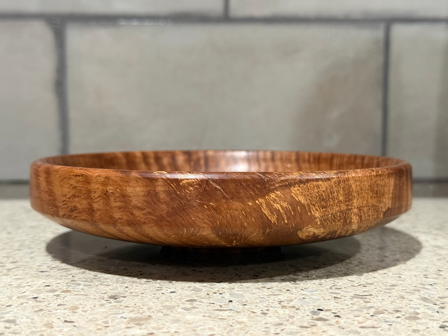 Wooden bowl on a kitchen counter with a tiled wall background