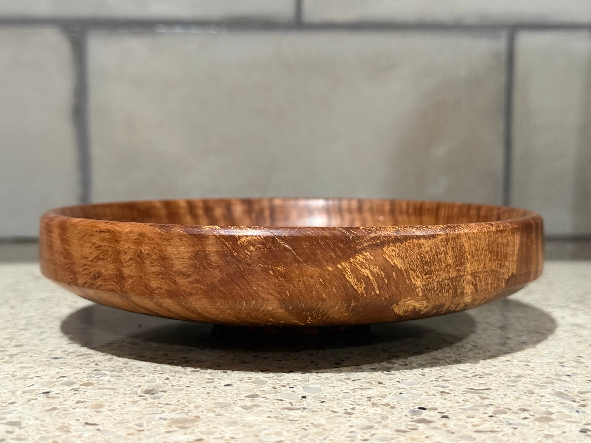 Wooden bowl on a kitchen counter with a tiled wall background