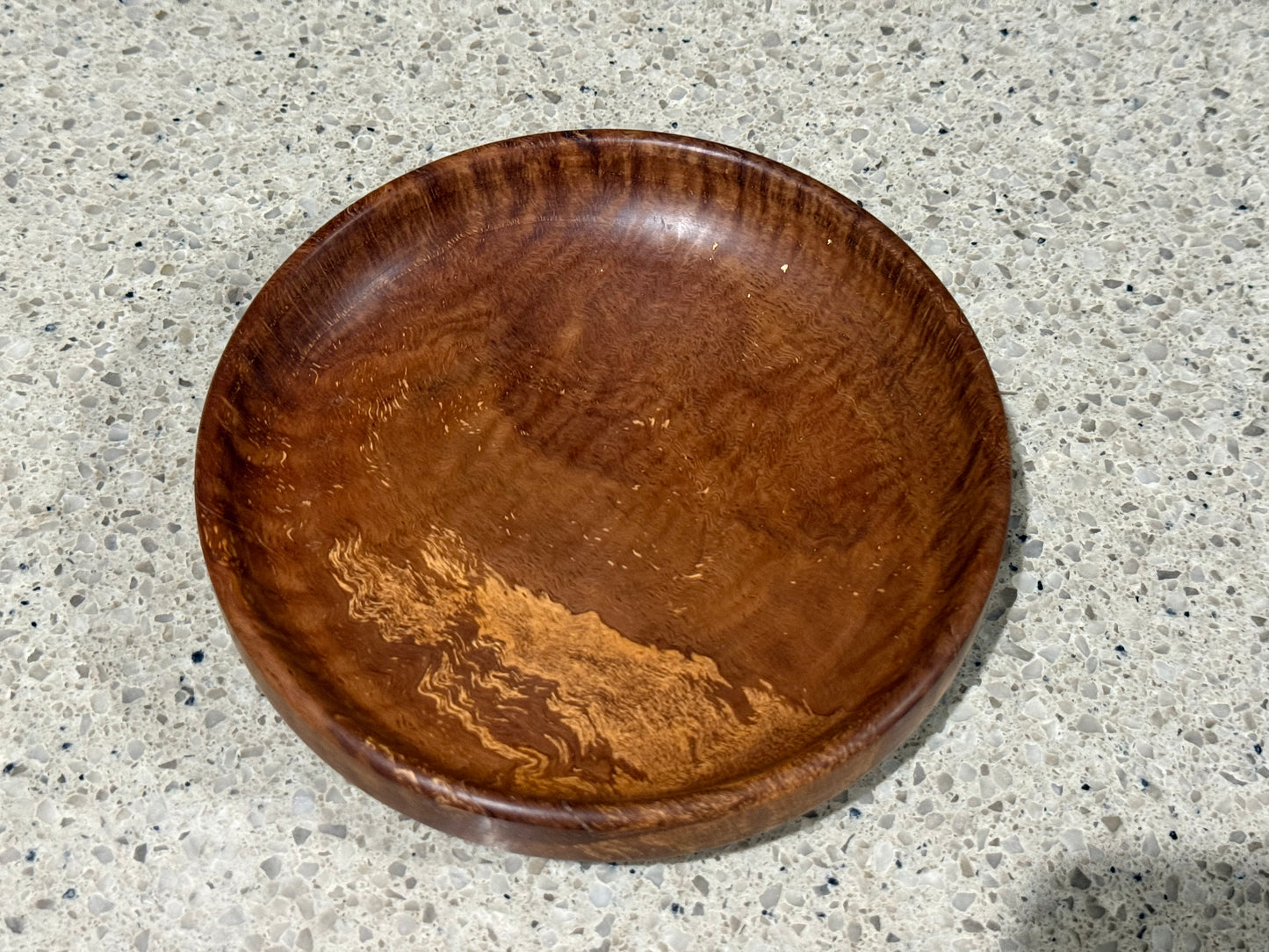 Wooden bowl on a kitchen counter with a tiled wall background