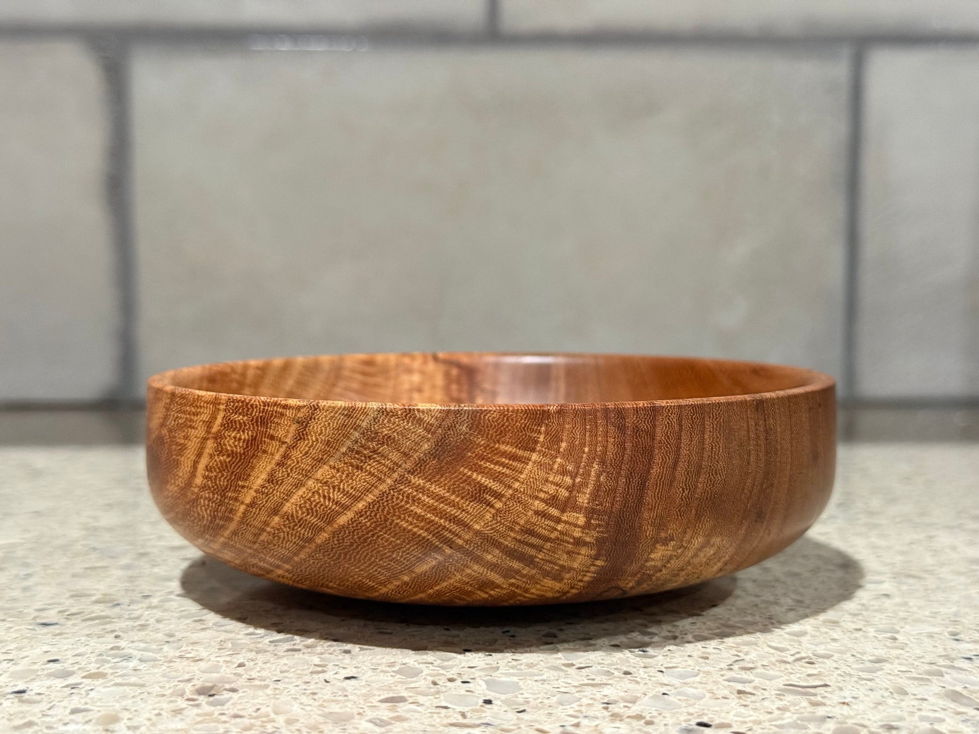 Wooden bowl on a kitchen counter with a tiled wall background