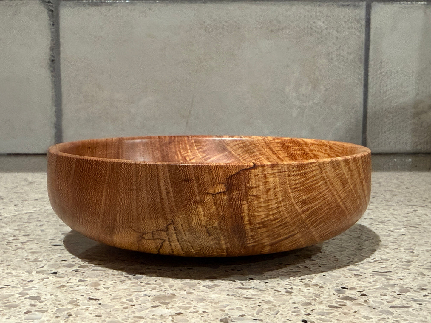 Wooden bowl on a kitchen counter with a tiled wall background