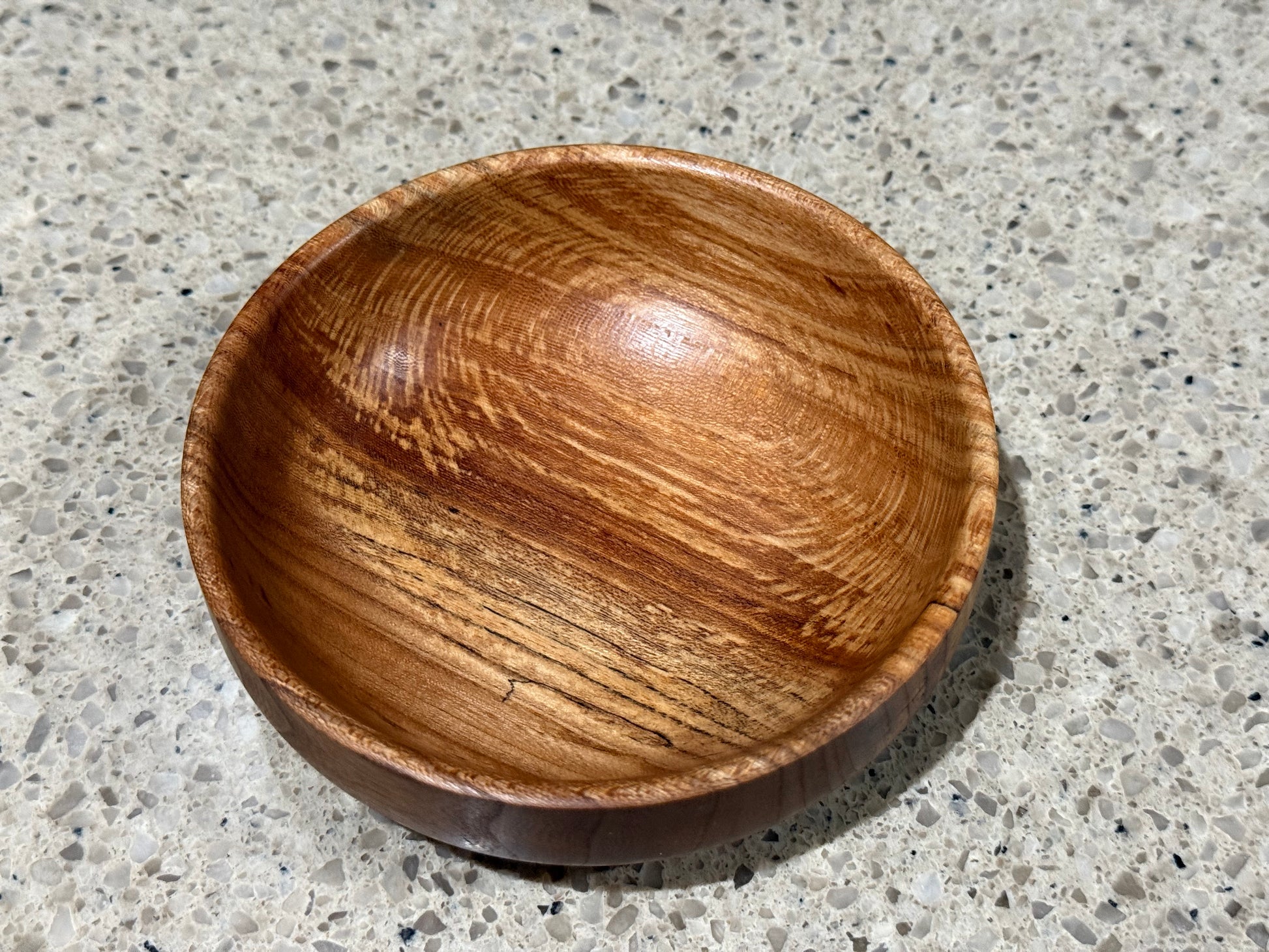 Wooden bowl on a kitchen counter with a tiled wall background