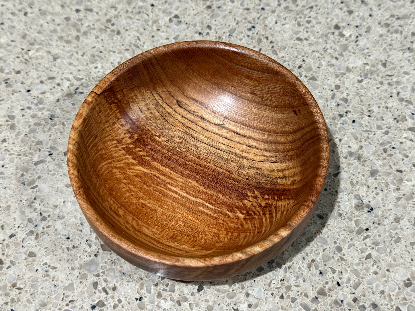 Wooden bowl on a kitchen counter with a tiled wall background